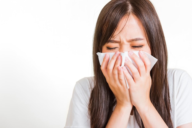 Portrait of Asian beautiful young woman sad she crying wipe the mucus with tissue, Close up of pretty girl sneezing sinus using towel to wipe snot from nose, studio shot isolated on white background