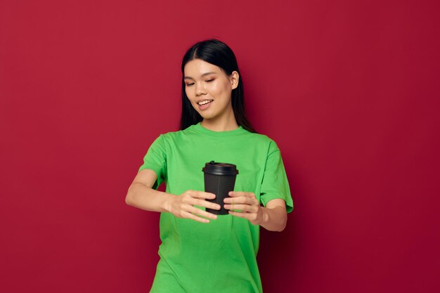 Portrait Asian beautiful young woman smile green tshirt black disposable cups fashion red background unaltered