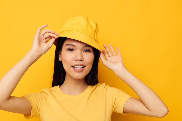 노란색 모자를 쓰고 있는 아름다운 아시아 여성의 초상화는 감정 노란색 배경을 그대로 유지하고 있습니다.