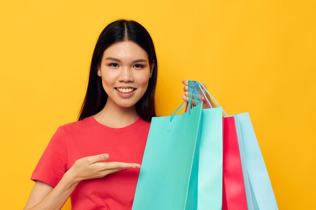 Portrait asian beautiful young woman with multicolored shopping bags yellow background unaltered