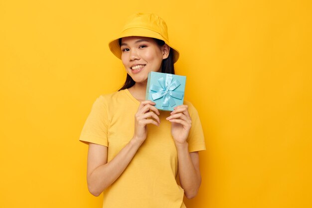 Portrait Asian beautiful young woman in a yellow Tshirt and a hat with a gift isolated background unaltered