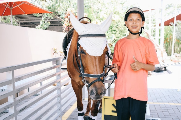 Portrait of Asian boy and a brown horse