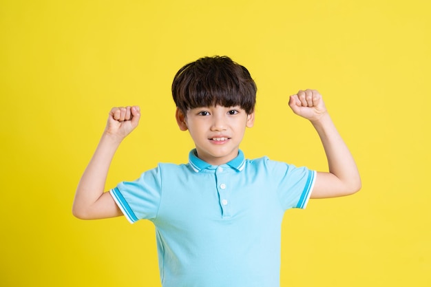 Portrait of an asian boy posing on a yellow background