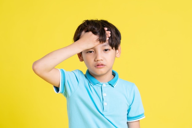 Портрет азиатского мальчика, позирующего на желтом фоне