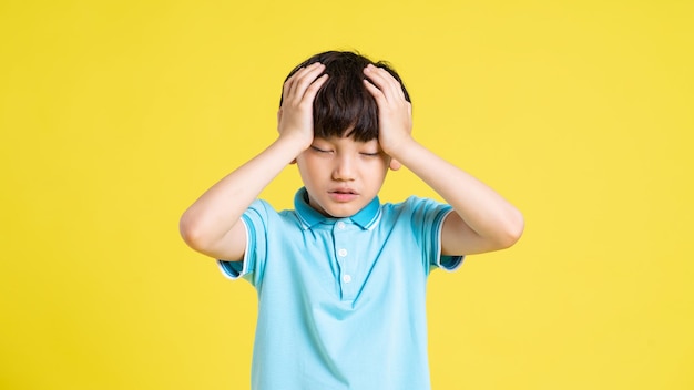 Photo portrait of an asian boy posing on a yellow background