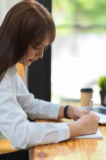 portrait of asian brunette female concentrating and writing on assignment business worker concept