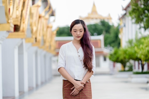 Ritratto asiatico donna buddista che indossa abiti tradizionali della thailandia stand in chiesa per il relax e la meditazione santuario ratchanatdaram bangkok