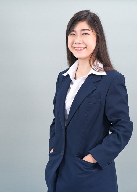 Портрет азиатской деловой женщины, стоящей изолированной на сером фоне