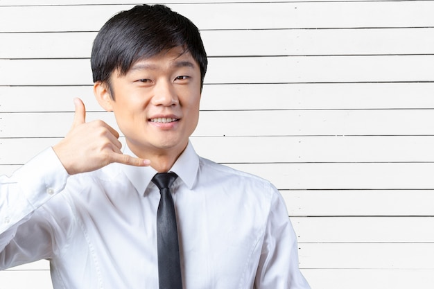 Portrait of an Asian businessman showing the 'call me' symbol