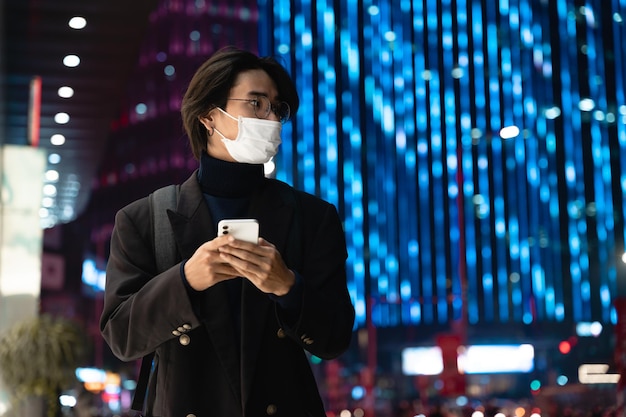 Portrait of an Asian businessman wearing a mask, in the street at night