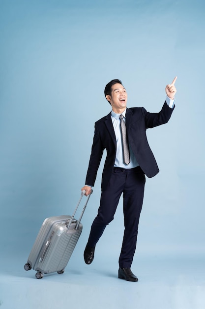 Portrait of Asian businessman wearing a suit and pulling a suitcase