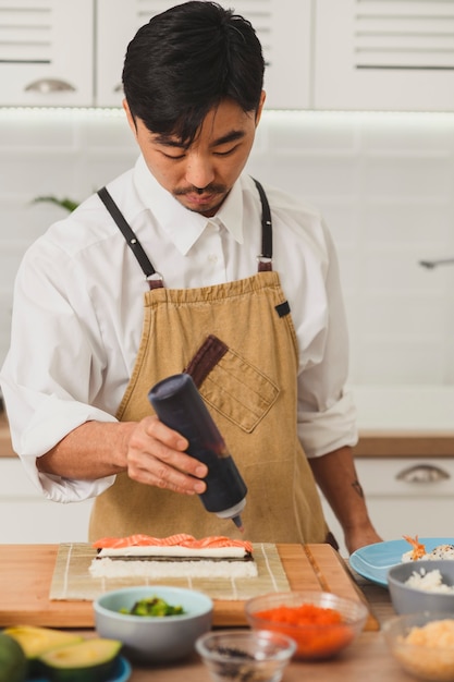 Portrait of asian chef making sushi sushi roll process adds sauce to sushi