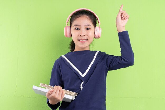 Portrait of Asian child holding book on green background