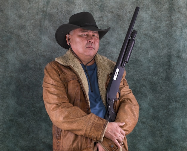 Photo portrait of asian cowboy with shotgun