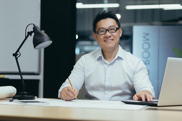 Портрет азиатского дизайнера, творческого работника, смотрящего в камеру и улыбающегося, работающего в архитектуре