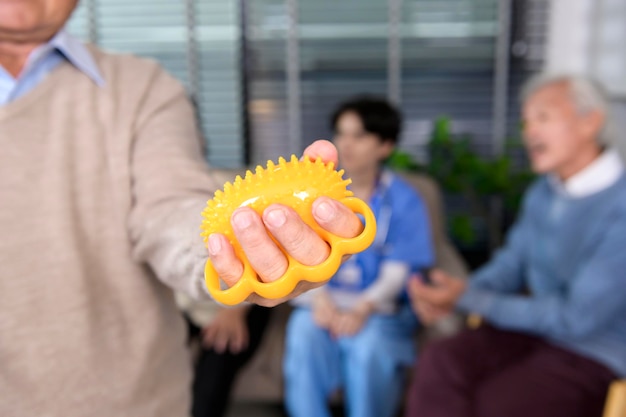 Portrait of asian elderly man doing hand exercise with hand\
stress ball at senior healthcare center