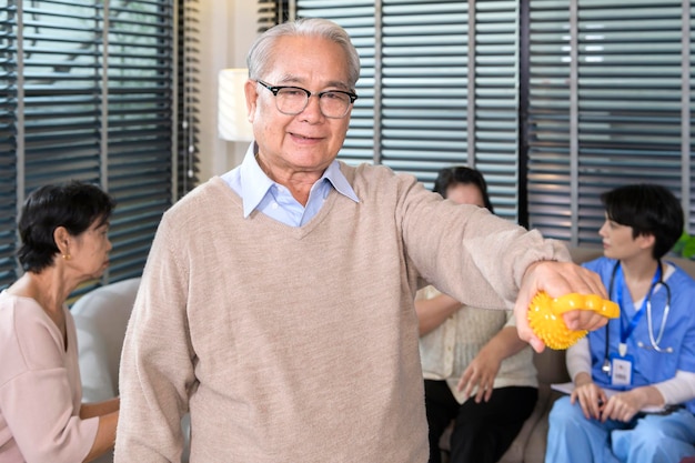 Портрет азиатского пожилого мужчины, выполняющего упражнения для рук с мячом для снятия стресса в медицинском центре для пожилых людей