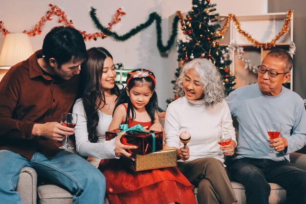 Portrait of Asian family exchanging presents during christmas at home Attractive happy people holding gift box celebrate holiday thanksgiving xmas eve tradition in living room in house together