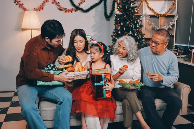 portrait of asian family exchanging presents during christmas at home attractive happy people holding gift box celebrate holiday thanksgiving xmas eve tradition in living room in house together