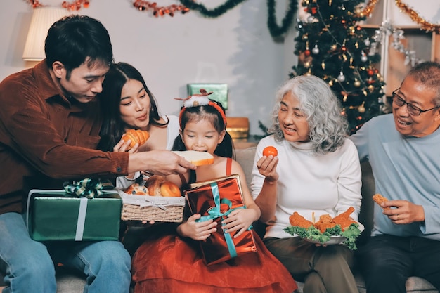 portrait of asian family exchanging presents during christmas at home attractive happy people holding gift box celebrate holiday thanksgiving xmas eve tradition in living room in house together