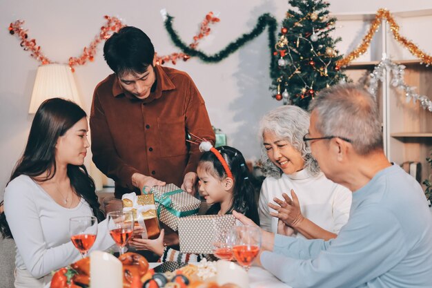 portrait of asian family exchanging presents during christmas at home attractive happy people holding gift box celebrate holiday thanksgiving xmas eve tradition in living room in house together