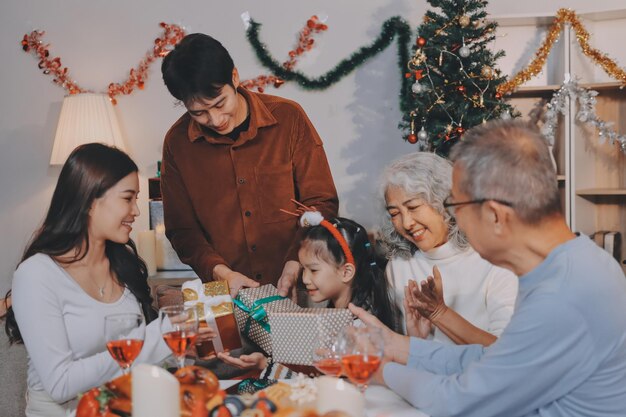 portrait of asian family exchanging presents during christmas at home attractive happy people holding gift box celebrate holiday thanksgiving xmas eve tradition in living room in house together