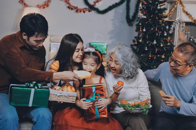 Portrait of Asian family exchanging presents during christmas at home Attractive happy people holding gift box celebrate holiday thanksgiving xmas eve tradition in living room in house together