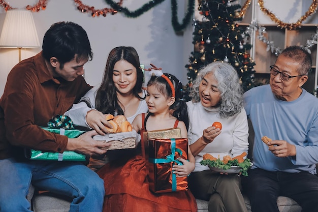 portrait of asian family exchanging presents during christmas at home attractive happy people holding gift box celebrate holiday thanksgiving xmas eve tradition in living room in house together