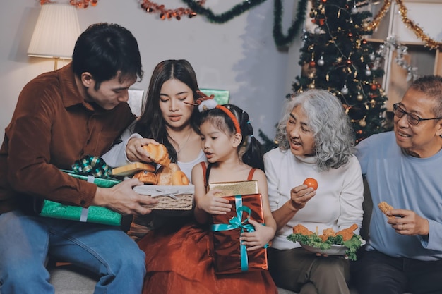 portrait of asian family exchanging presents during christmas at home attractive happy people holding gift box celebrate holiday thanksgiving xmas eve tradition in living room in house together