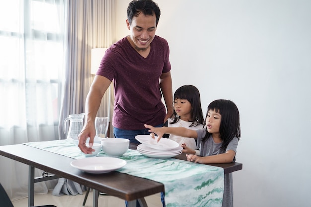 夕食のためにダイニングテーブルを準備するアジアの父と小さな娘の肖像画