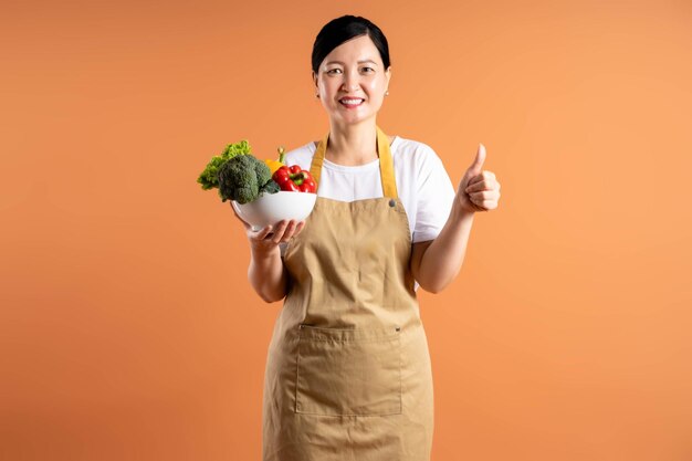 Portrait of asian female housewife posing on brown background