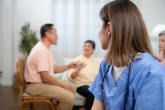 Portrait of Asian female nurse using digital tablet in nursing home with senior people on background