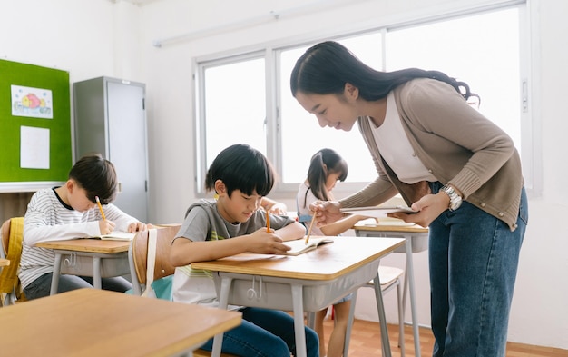 Portrait of asian female teacher helping elementary school boy in classroom at school education elementary school learning concept