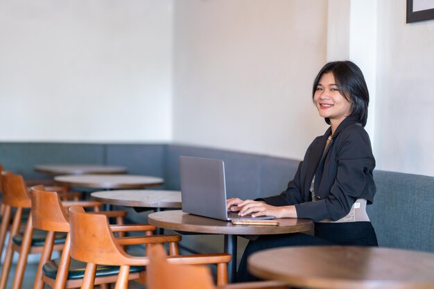 Photo portrait of asian freelance people businesswoman casual working with laptop computer in cafe interior in coffee shop backgroundbusiness expressed confidence embolden and successful concept