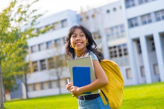 手にブロックと大学で笑顔のバックパックを持つキャンパス学生のアジアの女の子の肖像画