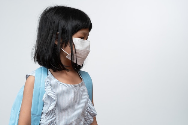 Portrait of Asian girl kid with protective face mask and school backpack ready for school