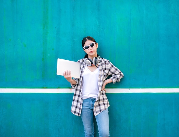 portrait of Asian girl student with laptop headphones and wear sunglasses