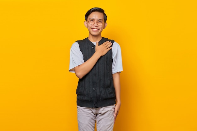 Portrait of Asian handsome young man greeting with big smile on his face on yellow background