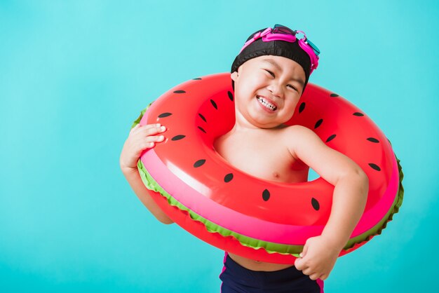 Portrait Asian happy cute little child boy wear goggles and swimsuit hold watermelon inflatable ring