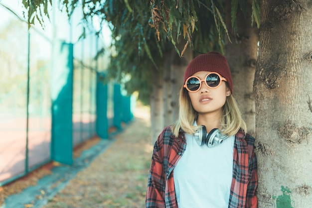 Il ritratto di una ragazza asiatica hipster indossa occhiali da sole arancioni in stile vintage. persone della thailandia. stile di vita della signora moderna