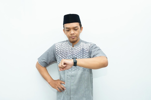 Portrait of an Asian Indonesian Muslim man pointing to smart watch for on time concept
