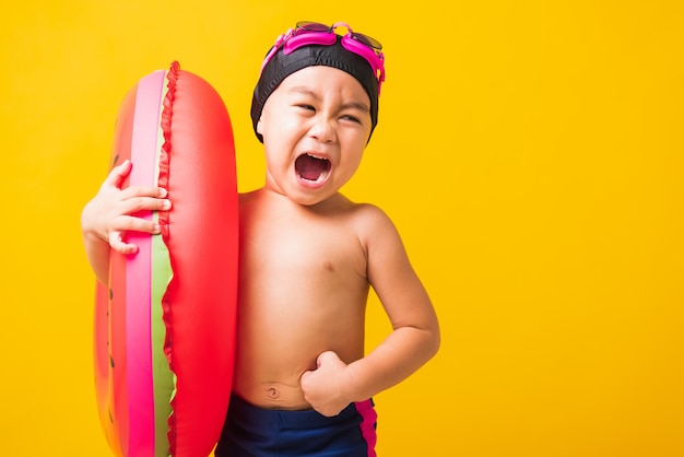 Portrait Asian little child boy wear goggles and swimsuit hold watermelon inflatable ring