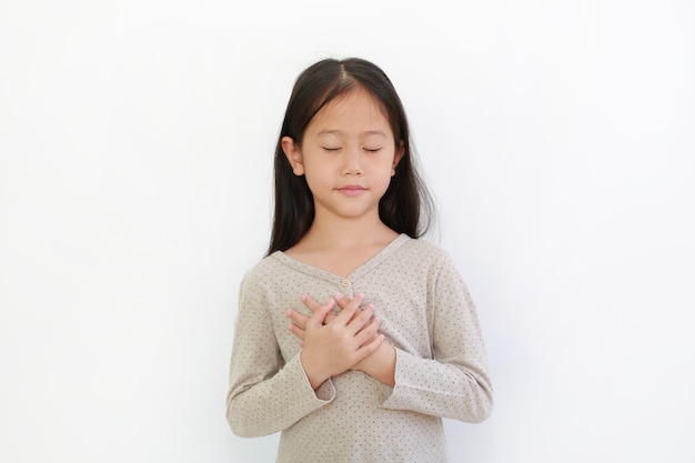 Portrait of Asian little girl closed eyes and holding hands on heart gesture of love