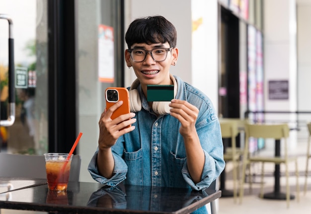 コーヒー ショップで座っているアジアの男子学生の肖像画