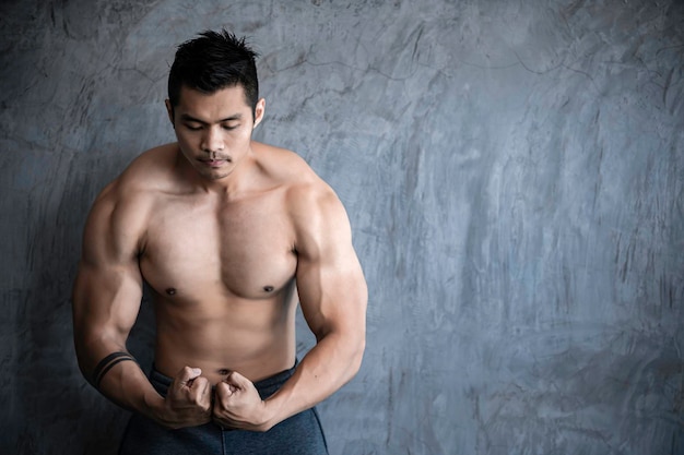 Portrait of asian man big muscle at the gymthailand\
peopleworkout for good healthybody weight trainingfitness at the\
gym concept