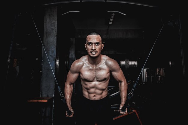 Portrait of asian man big muscle at the gymThailand peopleWorkout for good healthyBody weight trainingFitness at the gym conceptPrank to abdominal musclesLift up dumpbell