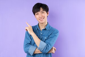 Portrait of asian man in blue shirt posing on purple background