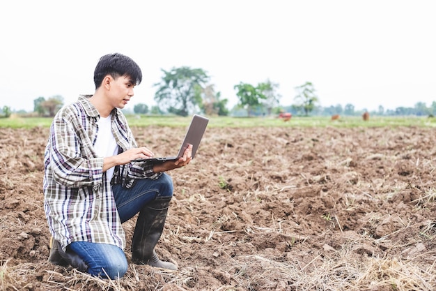 朝の農業田んぼでデジタルラップトップを使用して肖像画アジア人農家