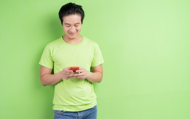 Портрет азиатского мужчины в зеленой футболке позирует на зеленом