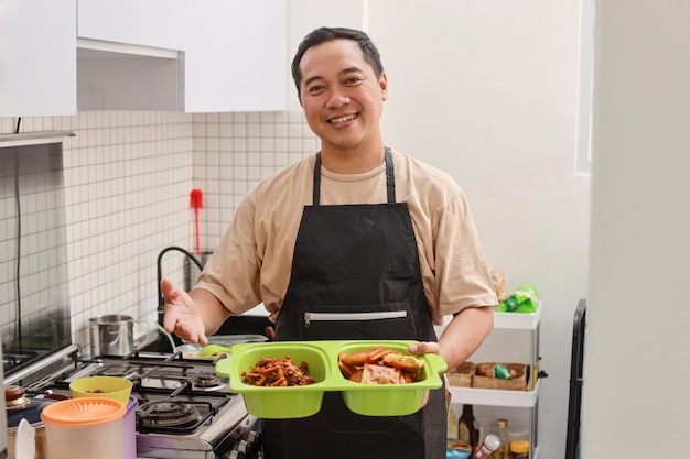 Portrait of Asian man serving food for lunch in the home kitchen